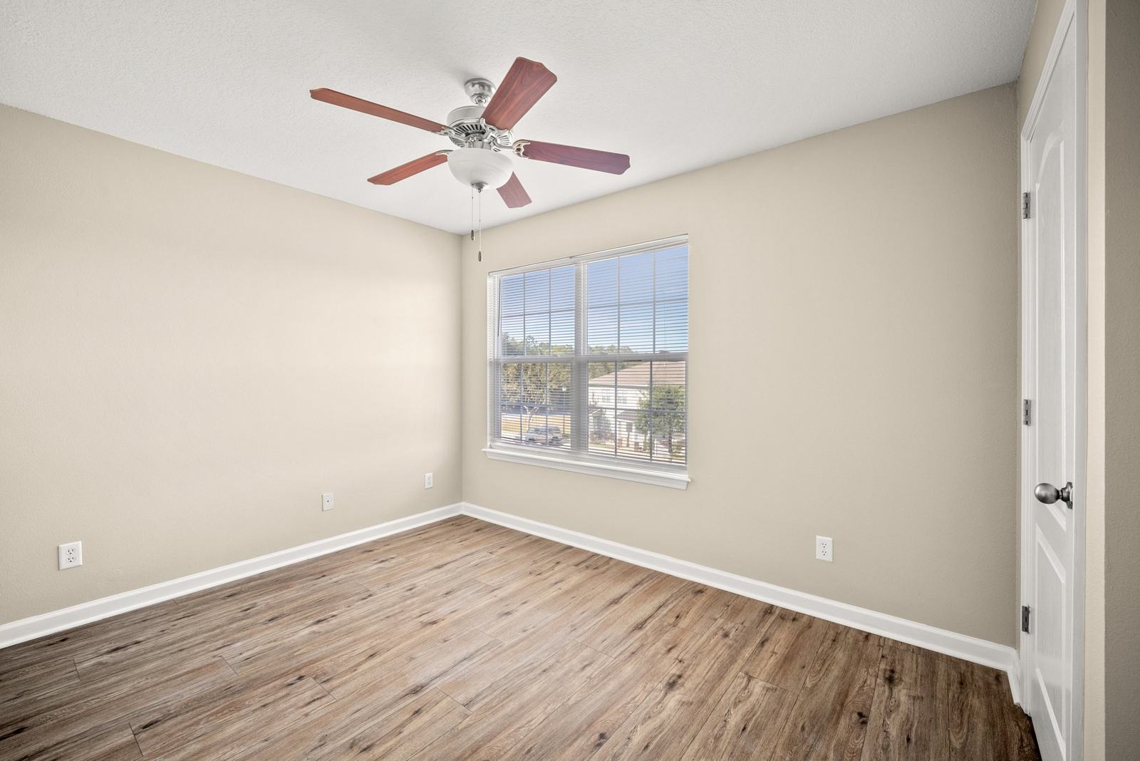 Bedroom with large window, ceiling fan and wood-look floors